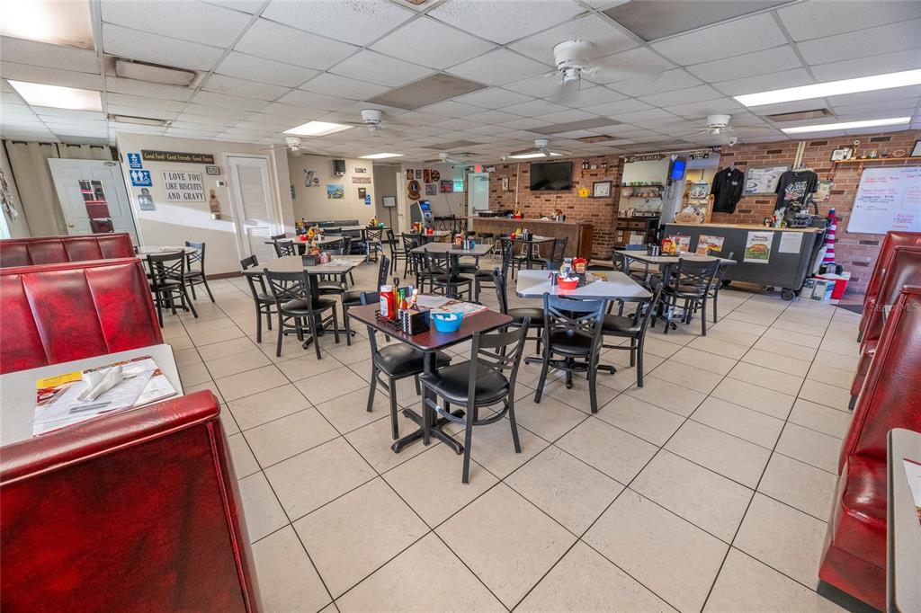 A restaurant dining room features red vinyl booths, square tables, and a brick accent wall — 966 REED CANAL ROAD, SOUTH DAYTONA, FL