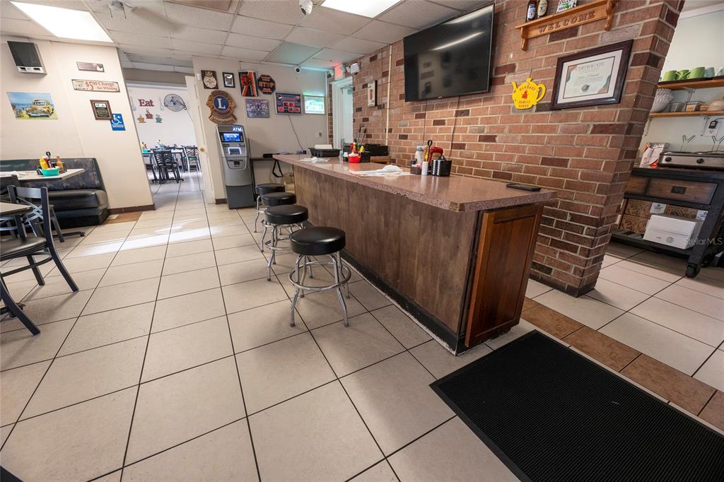 A restaurant interior features a brick wall, a long counter with stools, and tiled flooring — 966 REED CANAL ROAD, SOUTH DAYTONA, FL