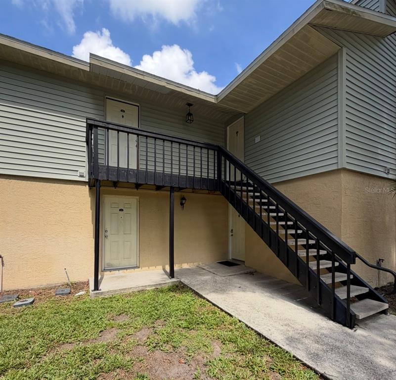 An exterior view of a two-story building featuring a wooden staircase leading to an upper balcony — 245 RED MAPLE PLACE, BRANDON, FL