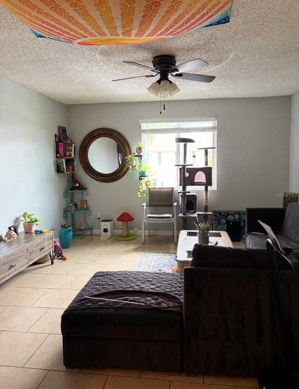 A living room features tile flooring, a ceiling fan, a round mirror, and a cat tree — 245 RED MAPLE PLACE, BRANDON, FL