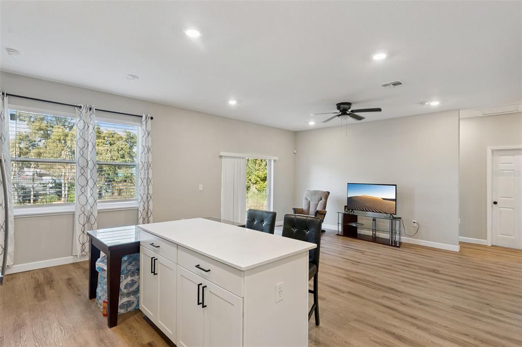 A kitchen island with white cabinets sits in an open-concept living area with wood flooring — 1403 W KALEY AVENUE, ORLANDO, FL