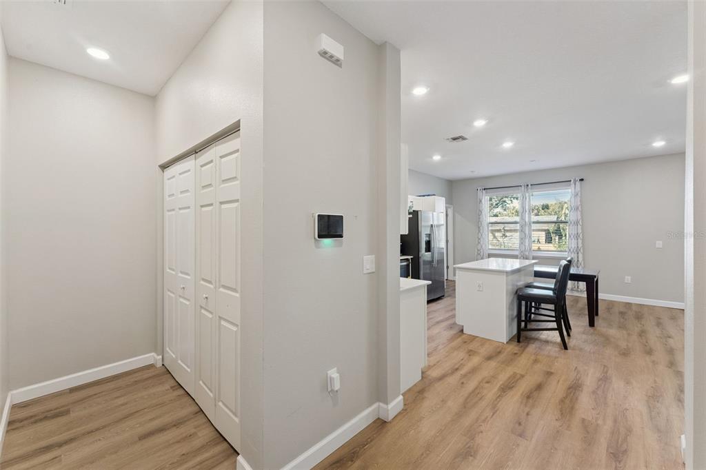 A hallway with a closet leads into an open-concept kitchen with a white island — 1403 W KALEY AVENUE, ORLANDO, FL
