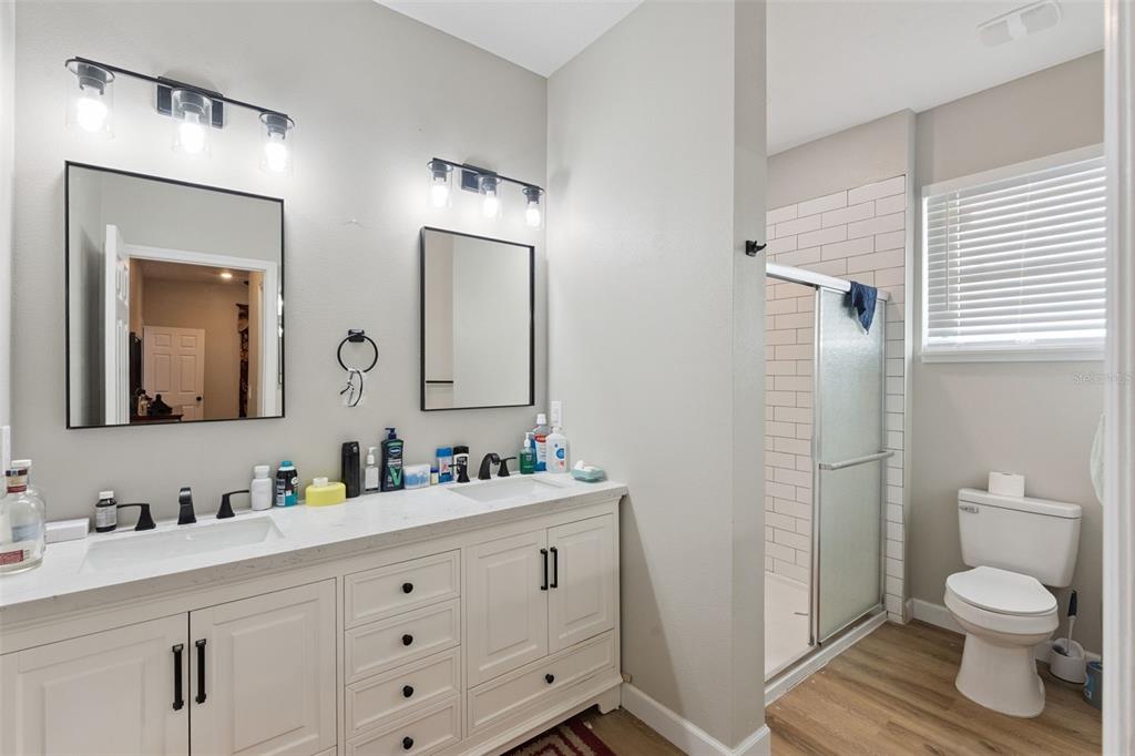A bathroom features a double vanity with white cabinets, two mirrors, and a walk-in shower — 1403 W KALEY AVENUE, ORLANDO, FL