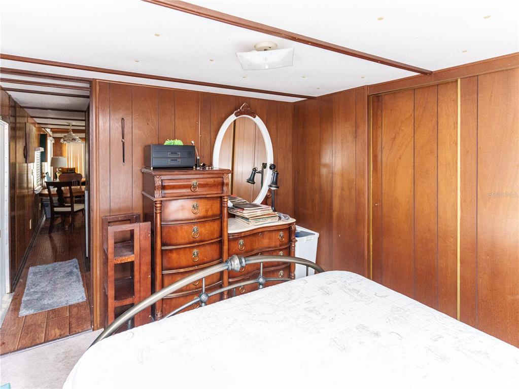 A bedroom features wood-paneled walls, a tall dresser with a mirror, and a metal bed frame — 5539 OAK RIDGE AVENUE, NEW PORT RICHEY, FL