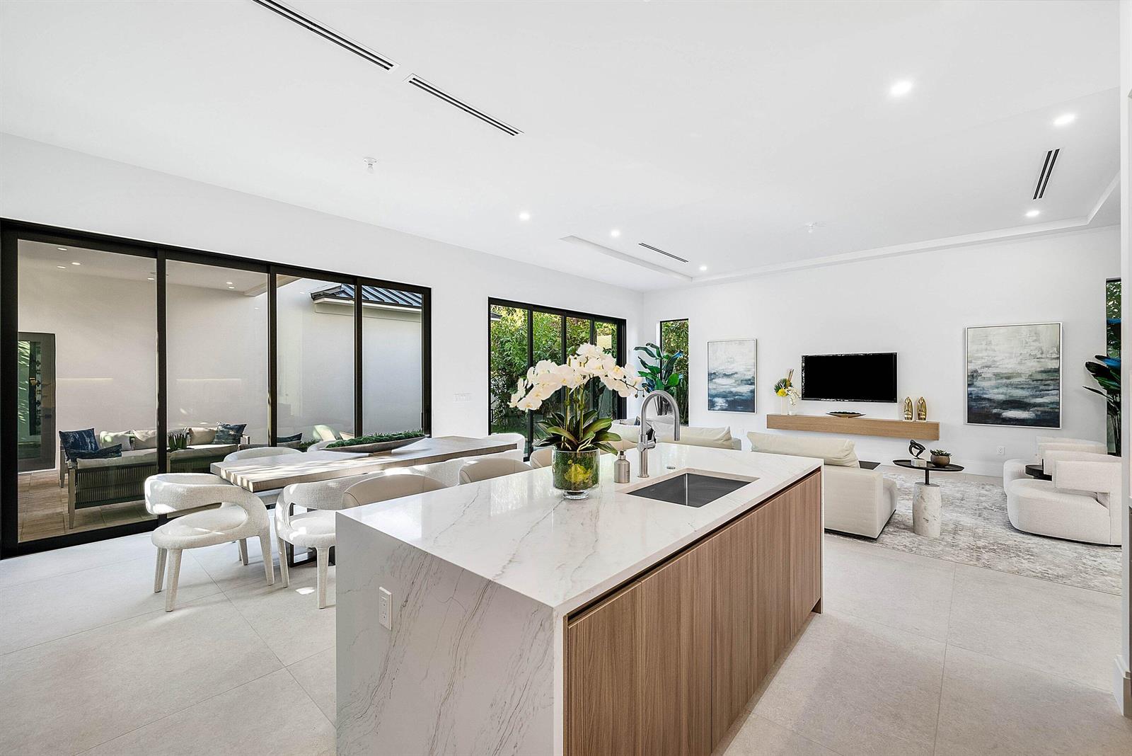 A modern open-concept kitchen and living area features a marble island, dining table, and patio — 222 SE 5th Street, Delray Beach FL 33483, DELRAY BEACH, FL