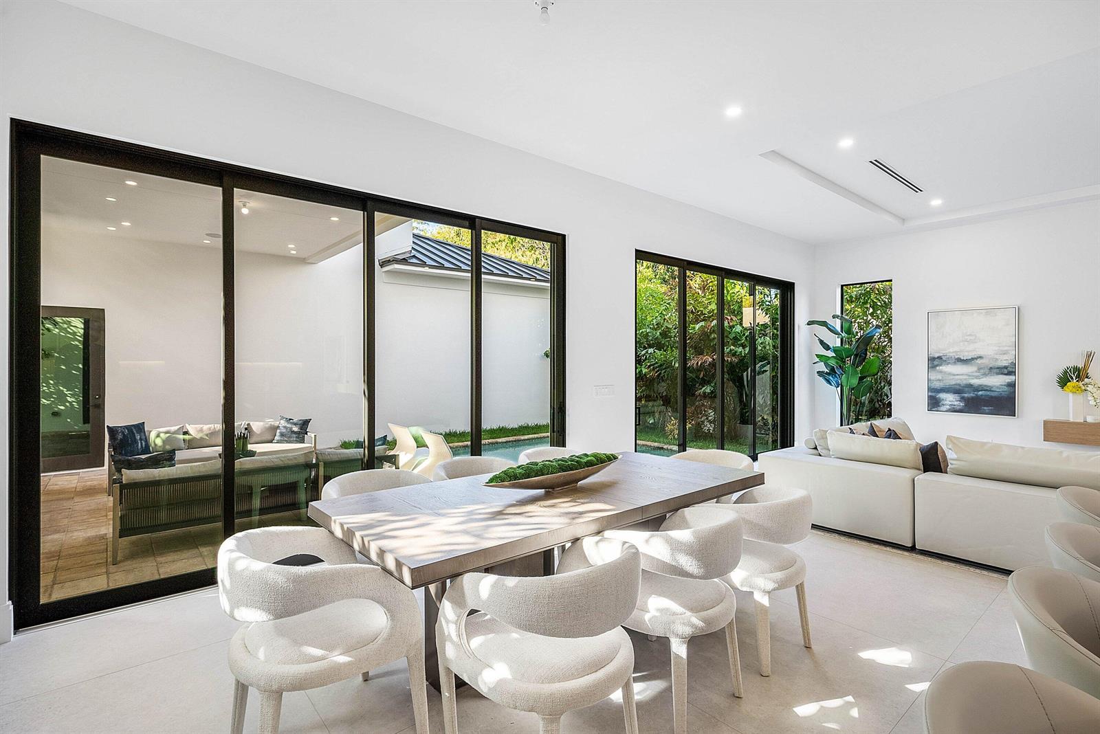 A modern kitchen features white upper cabinets, wood-toned lower cabinets, and a central island with seating — 222 SE 5th Street, Delray Beach FL 33483, DELRAY BEACH, FL