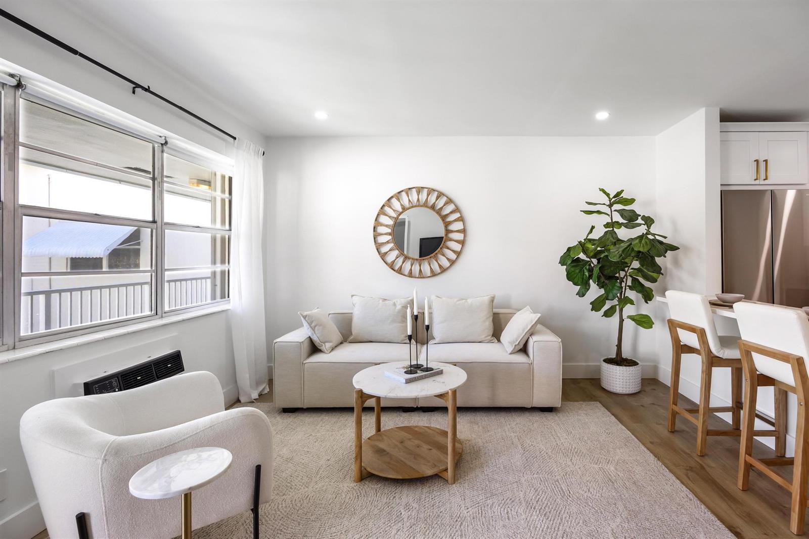 A bright living room features a beige sofa, round coffee table, and a large potted plant — 480 Horizons W # 207, Boynton Beach FL 33435, BOYNTON BEACH, FL