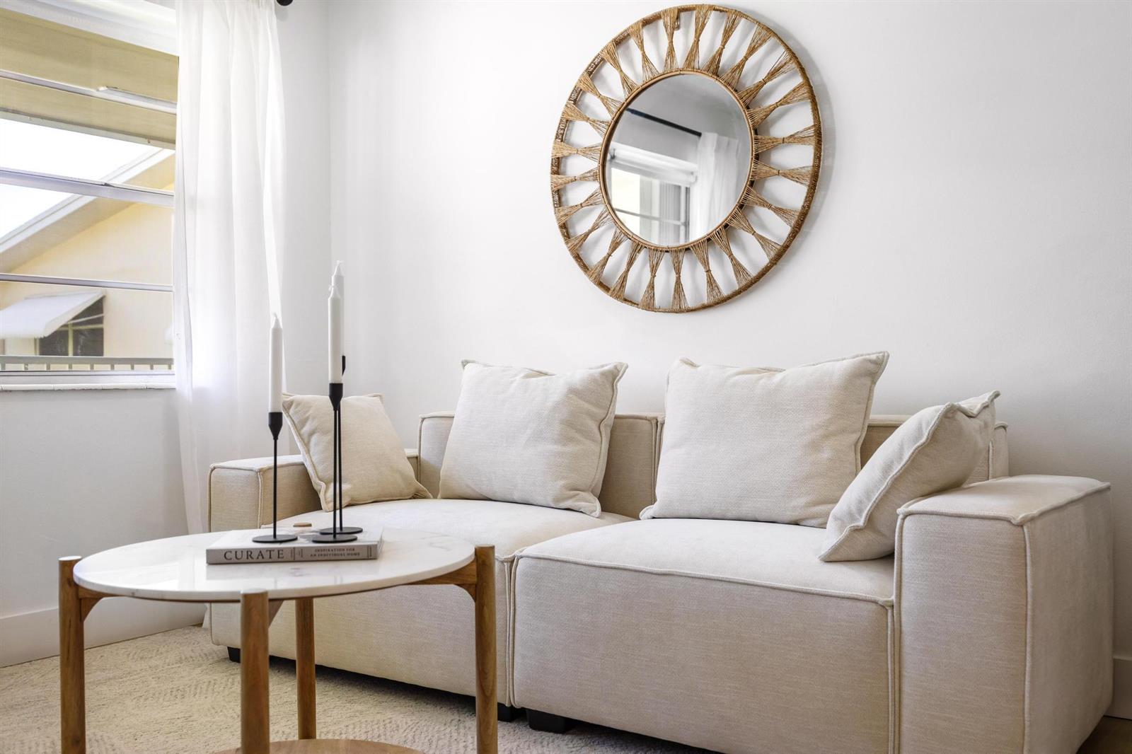 A living room features a beige modular sofa, a round marble coffee table, and a mirror — 480 Horizons W # 207, Boynton Beach FL 33435, BOYNTON BEACH, FL
