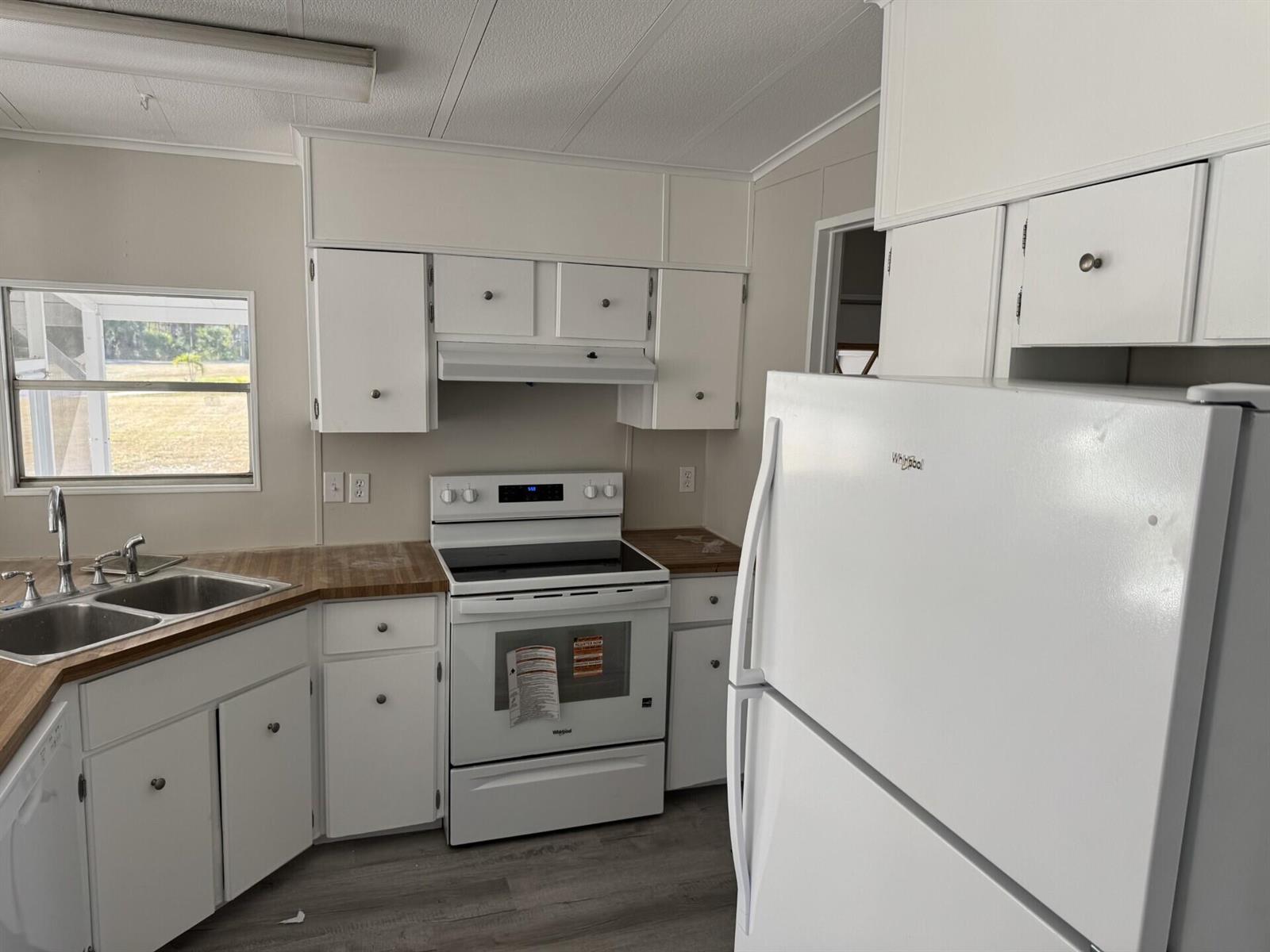 A kitchen features white cabinets, a white stove, a white refrigerator, and wood-look countertops — 4 San Felipe, Fort Pierce FL 34951, FORT PIERCE, FL