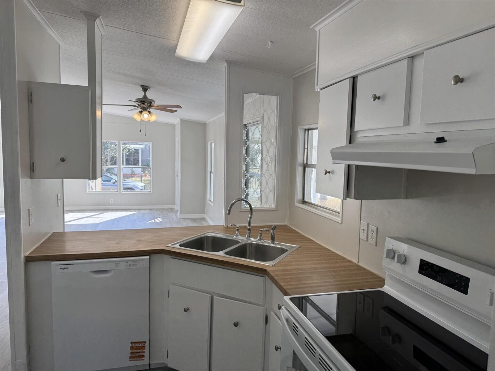 A kitchen with white cabinets, wood-look laminate countertops, and a view into the living area — 4 San Felipe, Fort Pierce FL 34951, FORT PIERCE, FL