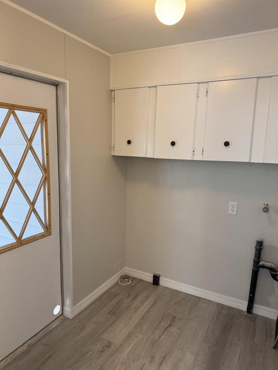 A laundry room features white upper cabinets, light gray walls, and wood-look vinyl flooring — 4 San Felipe, Fort Pierce FL 34951, FORT PIERCE, FL