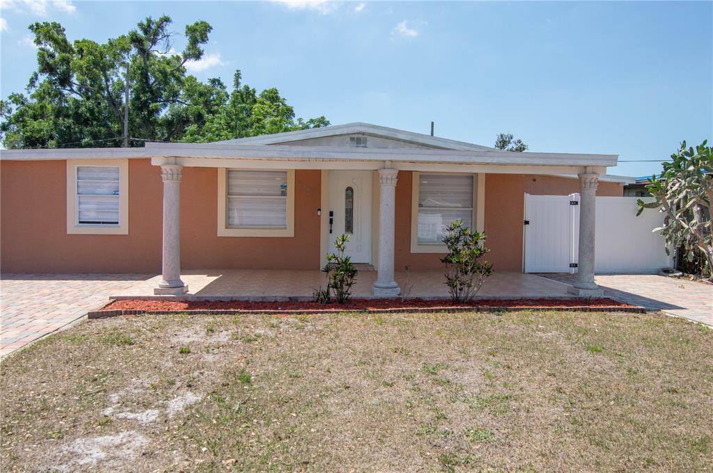 A single-story house with a peach-colored exterior, a covered front porch, and three decorative columns — 6506 SALINE STREET, TAMPA, FL