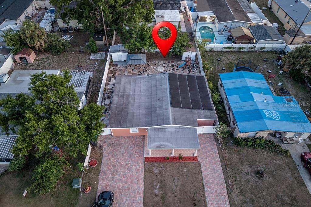 An aerial view shows a house with a paved driveway, solar panels, and backyard patio — 6506 SALINE STREET, TAMPA, FL