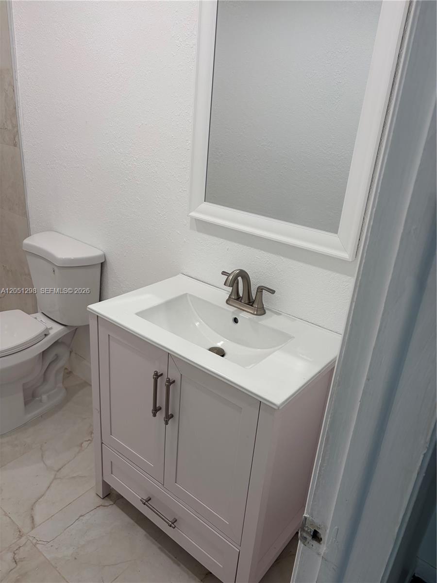 A bathroom features a white vanity with a sink, a mirror, and a toilet — 6980 NW 186th St # 525A, Hialeah FL 33015, HIALEAH, FL