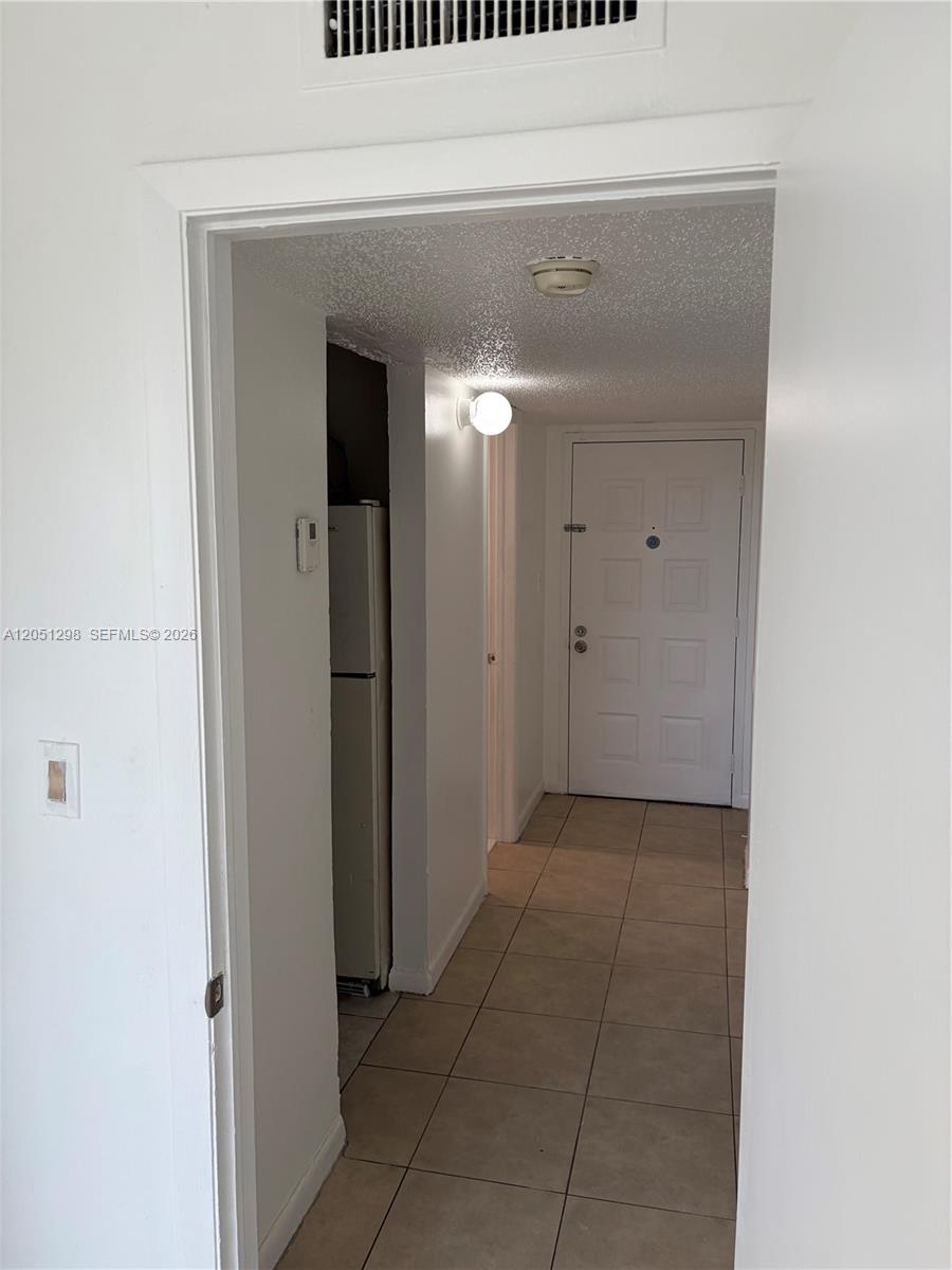 A tiled hallway leads to an entrance door with a refrigerator visible to the left — 6980 NW 186th St # 525A, Hialeah FL 33015, HIALEAH, FL