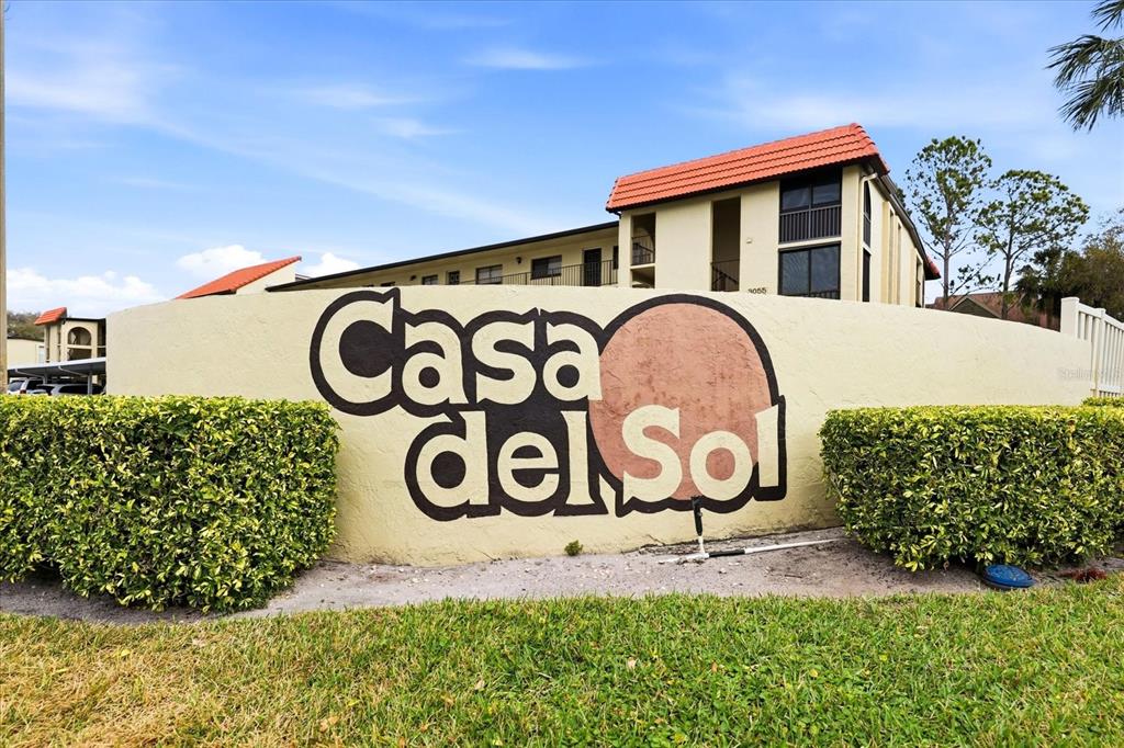 A low wall with the sign Casa del Sol stands before a multi-story apartment building — 2420 WINDING CREEK BOULEVARD UNIT 105, CLEARWATER, FL