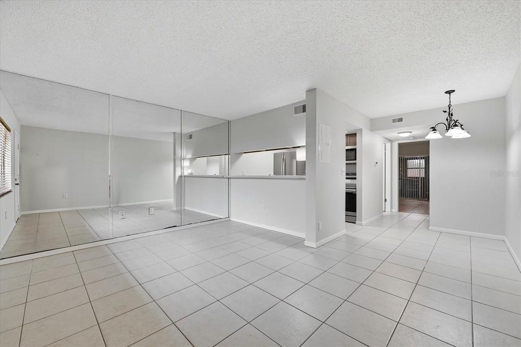 A tiled living room features a mirrored wall, a pass-through window, and a dining area — 2420 WINDING CREEK BOULEVARD UNIT 105, CLEARWATER, FL