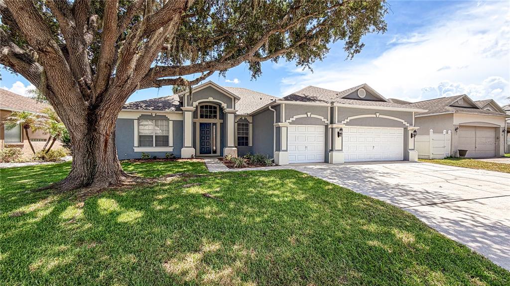 A single-story gray house with a large oak tree in the front yard — 123 GOLF COURSE PARKWAY, DAVENPORT, FL