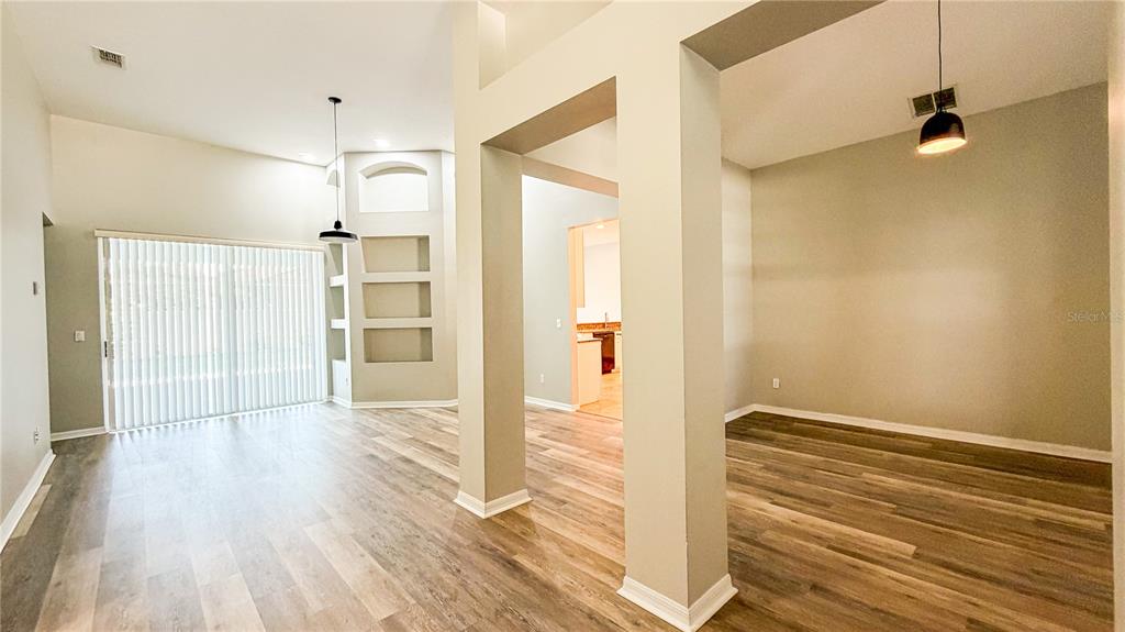 An open-concept living area features light wood-look flooring, neutral walls, and a recessed display niche — 123 GOLF COURSE PARKWAY, DAVENPORT, FL