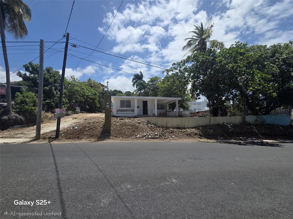 A single-story house with a covered porch sits behind a dirt yard and low wall — 144 CARRETERA 3, CEIBA, PR