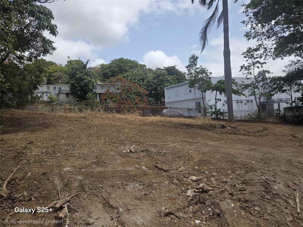 A vacant, cleared dirt lot with a chain-link fence and surrounding trees and buildings — 144 CARRETERA 3, CEIBA, PR