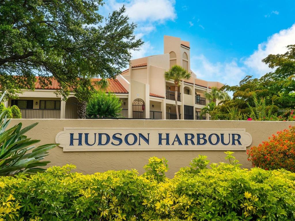 The exterior of the Hudson Harbour apartment complex features a tan stucco building with balconies — 800 HUDSON AVENUE UNIT 106, SARASOTA, FL