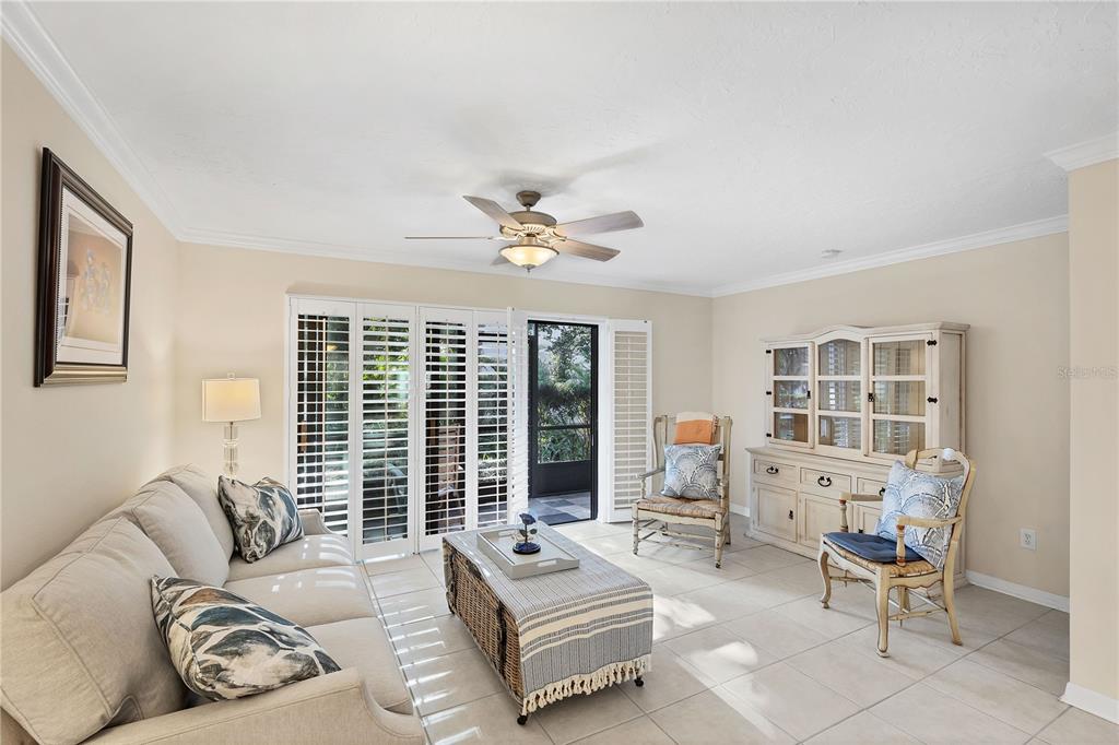 A living room features a beige sofa, a wicker coffee table, and two wooden chairs — 800 HUDSON AVENUE UNIT 106, SARASOTA, FL