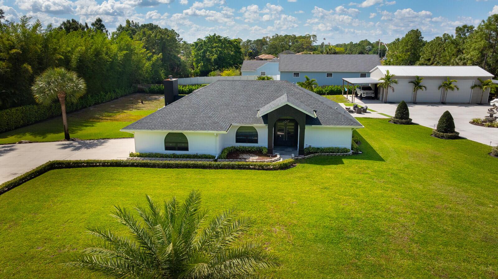 A dining area with a glass table and gray chairs sits beside a living room — 16966 91st Place N, FL 33470, FL