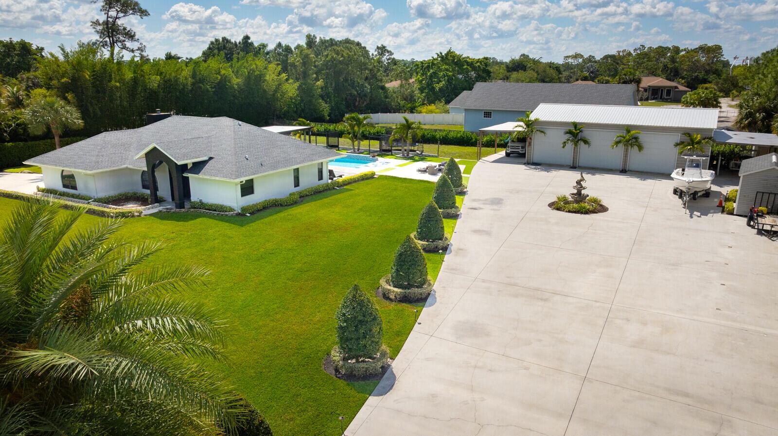 An aerial view shows a white house, a large concrete driveway, and a detached garage — 16966 91st Place N, FL 33470, FL