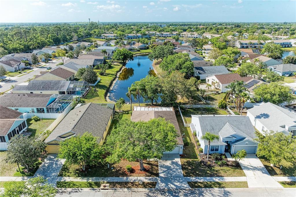 An aerial view shows a suburban neighborhood with houses surrounding a central pond — 4642 RUNABOUT WAY, BRADENTON, FL