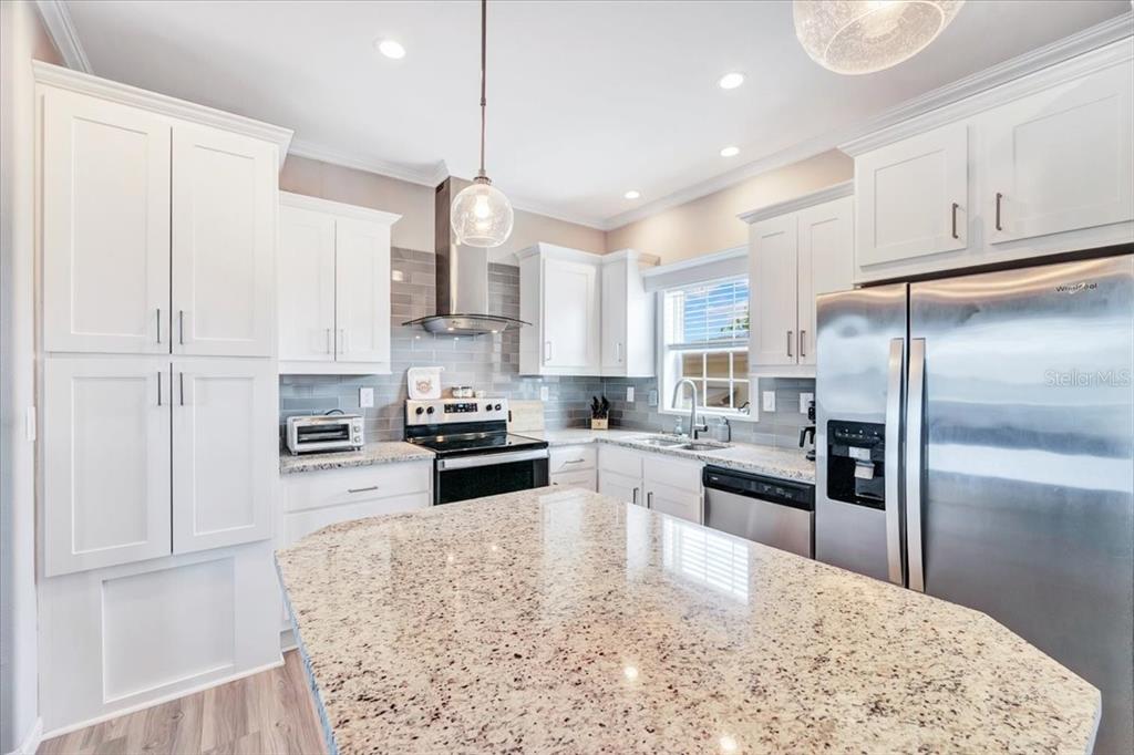 A kitchen features white cabinets, granite countertops, stainless steel appliances, and a central island — 20 BEAVERKILL DRIVE, LAKE WALES, FL