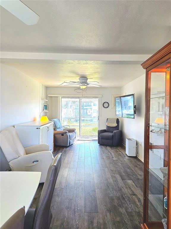 A living room features wood-look flooring, a ceiling fan, a glass display cabinet, and sliding doors — 1816 RESTFUL DRIVE UNIT M22, BRADENTON, FL