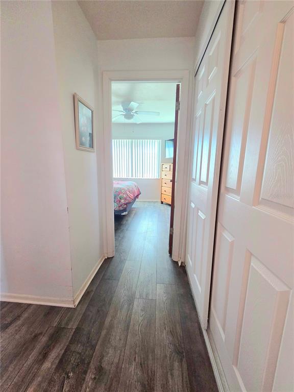 A hallway with wood-look flooring leads into a bedroom with a ceiling fan and dresser — 1816 RESTFUL DRIVE UNIT M22, BRADENTON, FL