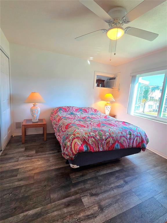 A bedroom features a bed with a colorful patterned quilt, wood-look flooring, and a ceiling fan — 1816 RESTFUL DRIVE UNIT M22, BRADENTON, FL