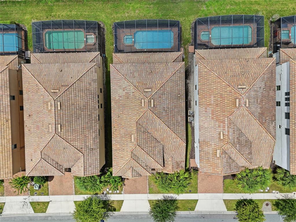 An aerial view shows three houses with tiled roofs, screened-in pools, and front-facing driveways — 1610 LIMA AVENUE, KISSIMMEE, FL