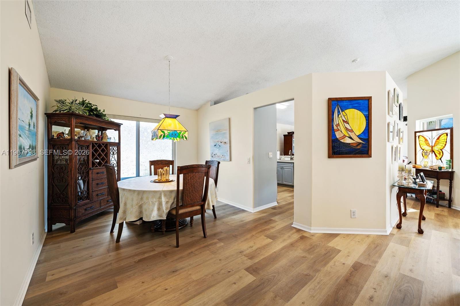 A dining area features a round table, wooden chairs, a stained-glass lamp, and wood flooring — 372 NW 45th Ter, Deerfield Beach FL 33442, DEERFIELD BEACH, FL