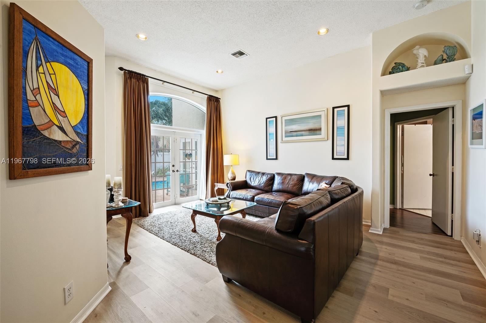 A living room features a brown leather sectional, glass coffee table, and patio door access — 372 NW 45th Ter, Deerfield Beach FL 33442, DEERFIELD BEACH, FL