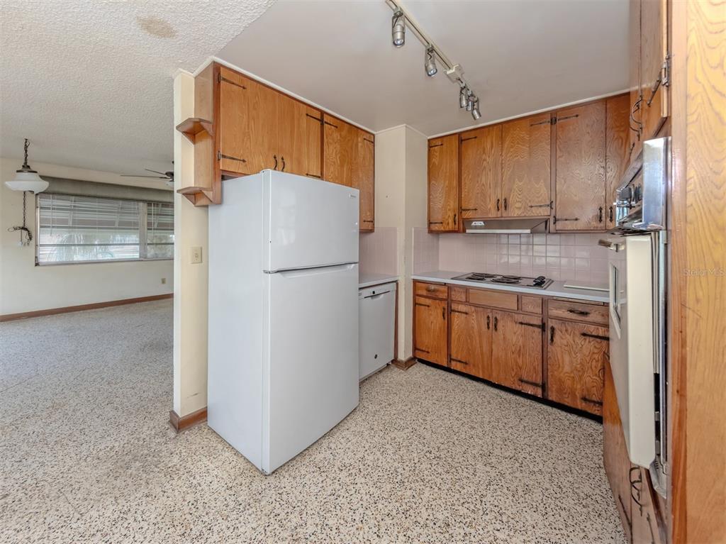 A kitchen features wood cabinets, a white refrigerator, a built-in oven, and speckled flooring — 730 S VENICE BOULEVARD, VENICE, FL