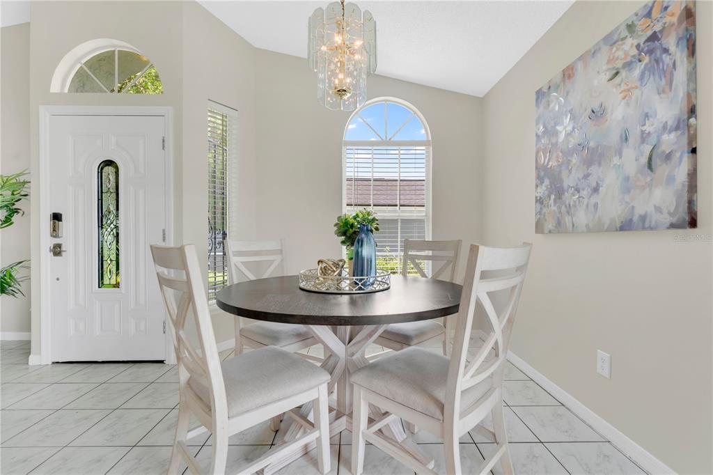A dining area features a round table with four chairs, a chandelier, and a large painting — 272 SAN GABRIEL STREET, WINTER SPRINGS, FL