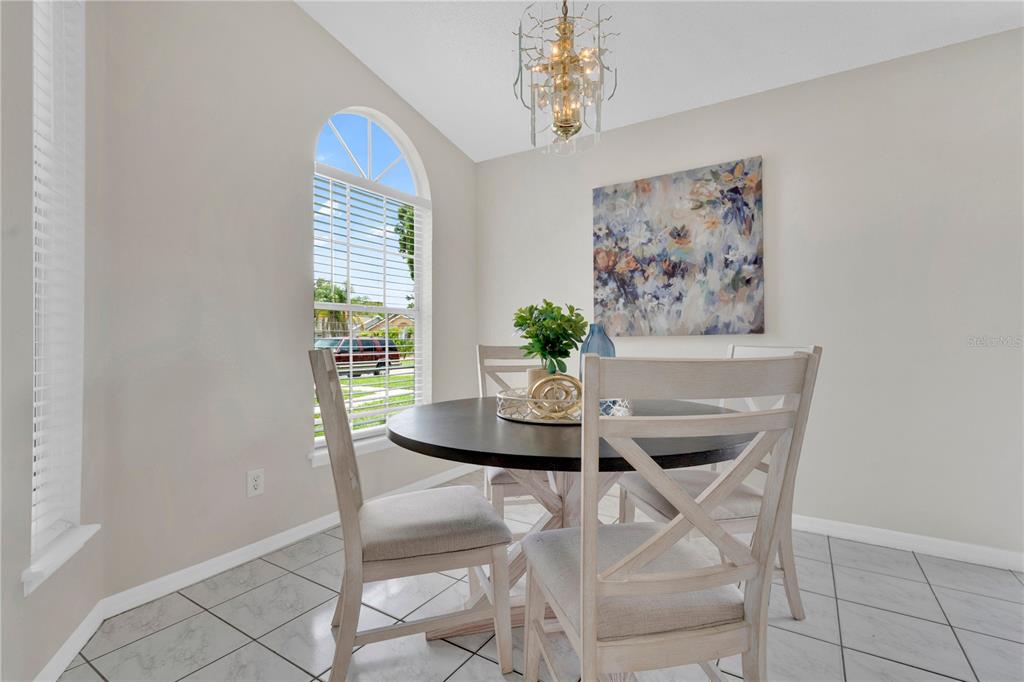 A dining area features a round table with four chairs, a chandelier, and an arched window — 272 SAN GABRIEL STREET, WINTER SPRINGS, FL