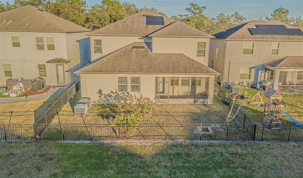 A rear exterior view of a two-story house with a screened-in patio and fenced yard — 6244 ENGLISH HOLLOW ROAD, TAMPA, FL