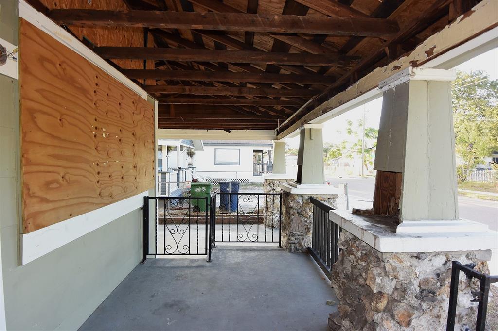 A covered porch features stone-based columns, a wooden ceiling, and a plywood-covered wall section — 913 E 28TH AVENUE, TAMPA, FL