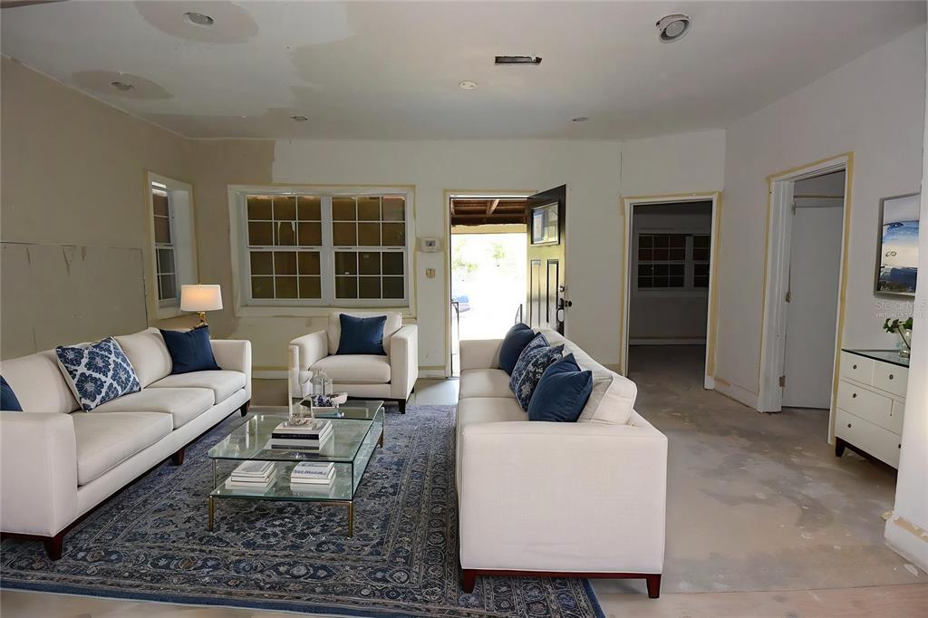 This living room features white sofas, a glass coffee table, and unfinished walls and floors — 913 E 28TH AVENUE, TAMPA, FL