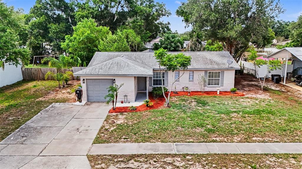 A single-story house with a gray roof, light-colored brick exterior, and a concrete driveway — 2022 LANCE COURT, DOVER, FL