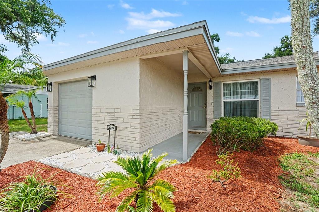 A single-story house with a beige stucco facade, stone accents, and a small front porch — 2022 LANCE COURT, DOVER, FL