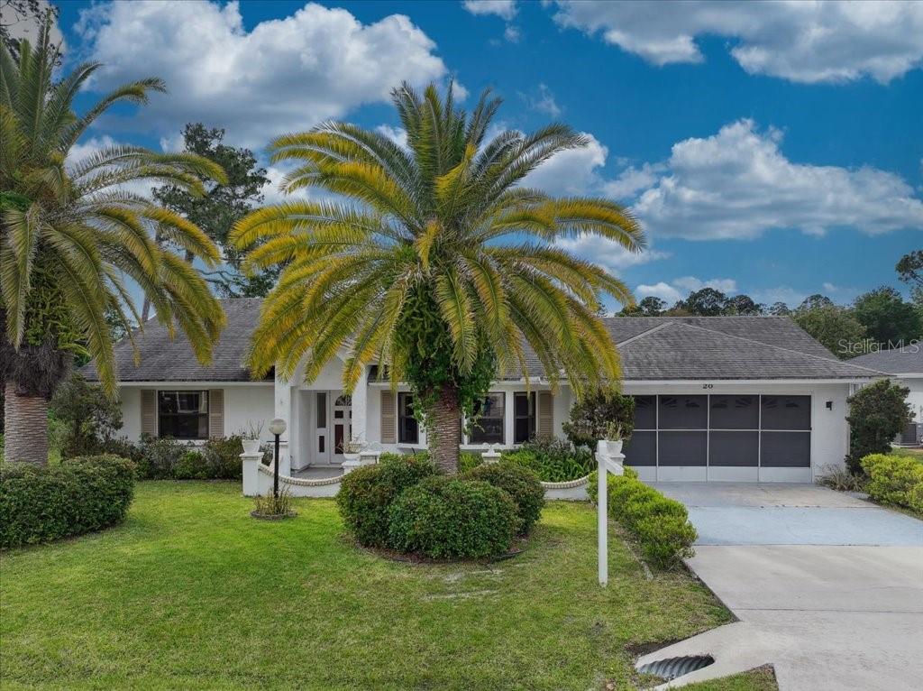 A single-story house with a white exterior, a two-car garage, and large palm trees — 20 FORSYTHE LANE, PALM COAST, FL