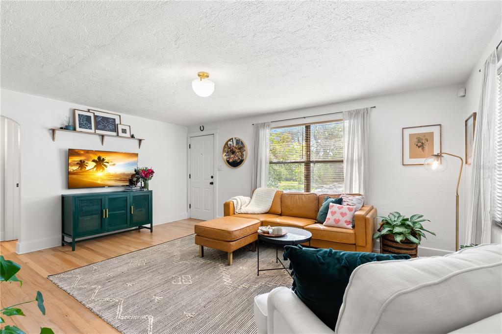 A living room features a tan leather sectional, a dark green media console, and hardwood floors — 837 42ND AVENUE N, ST PETERSBURG, FL