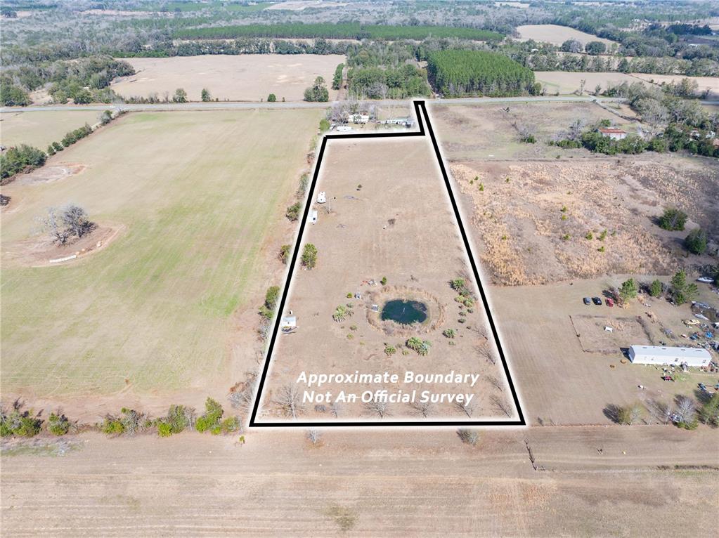 An aerial view shows a rural property with a pond and a marked boundary line — 3378 W STATE ROAD 238, LAKE BUTLER, FL