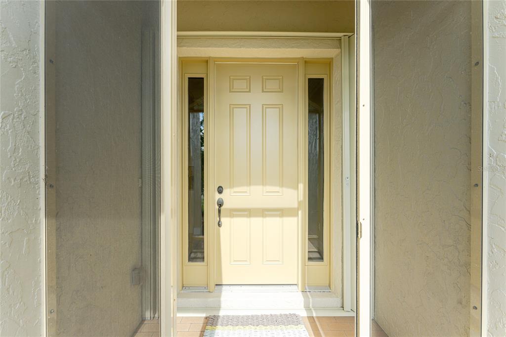 A light yellow front door with side windows is framed by a screen door — 413 TOMOKA DRIVE, ENGLEWOOD, FL