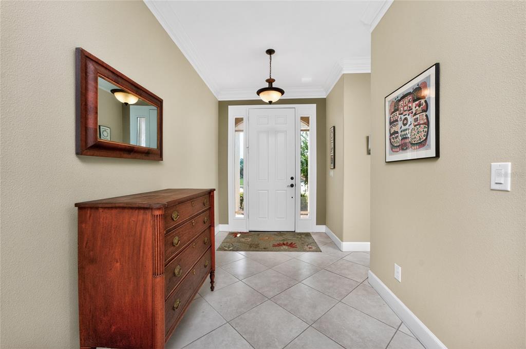 A foyer features a wooden dresser, a wall mirror, tile flooring, and a white front door — 413 TOMOKA DRIVE, ENGLEWOOD, FL